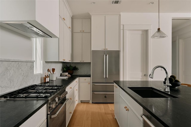 113 Nelray Blvd Unit 1, Austin, TX 78751 - kitchen with stainless steel appliances, a sink, light wood-type flooring, wall chimney range hood, and white cabinetry