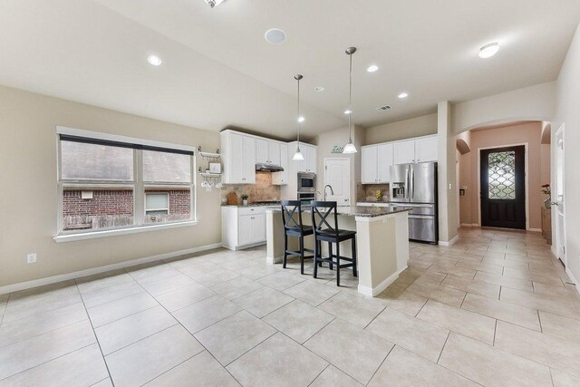 190 Stone View Trl, Austin, TX 78737 - kitchen with stainless steel appliances, arched walkways, white cabinetry, a breakfast bar area, and recessed lighting