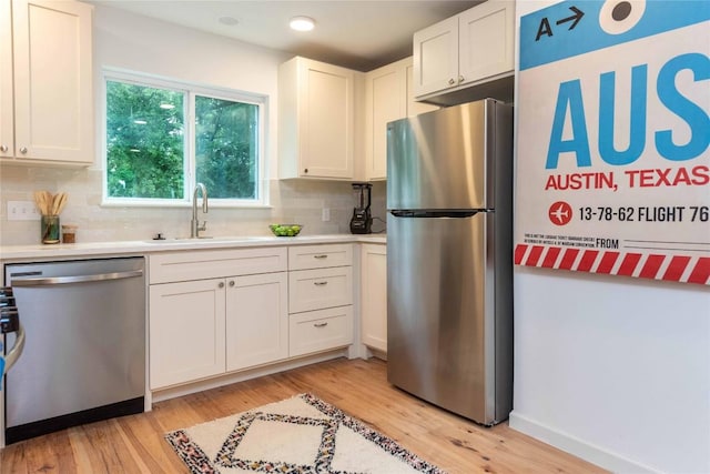 3801 Wilson St, Austin, TX 78704 - kitchen with appliances with stainless steel finishes, a sink, backsplash, light wood-style flooring, and white cabinets