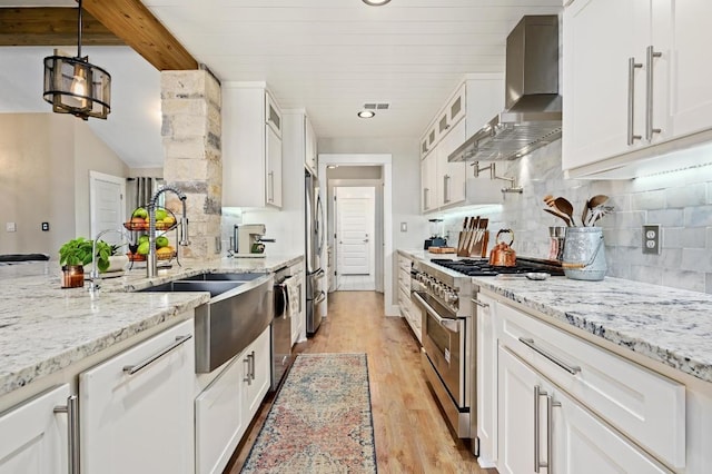 1011 County Road 149, Georgetown, TX 78626 - kitchen with wall chimney exhaust hood, stainless steel appliances, light wood finished floors, white cabinetry, and glass insert cabinets