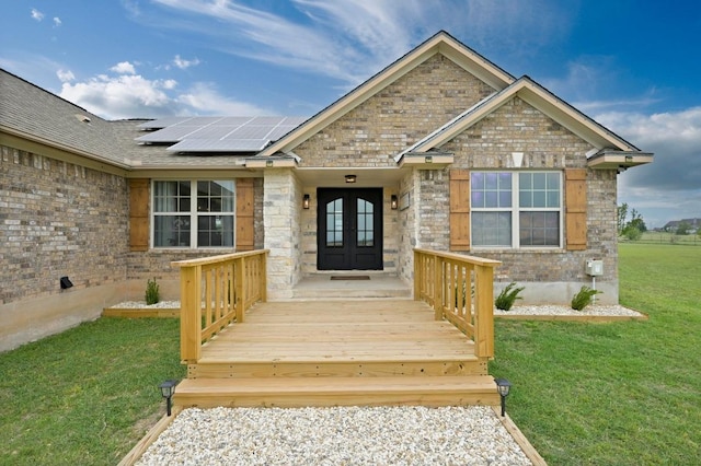 1011 County Road 149, Georgetown, TX 78626 - property entrance featuring french doors, a lawn, roof mounted solar panels, brick siding, and stone siding