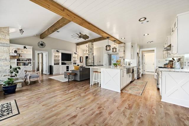 1011 County Road 149, Georgetown, TX 78626 - kitchen featuring stainless steel appliances, white cabinetry, open floor plan, light wood-type flooring, and a breakfast bar