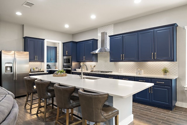 509 Leon Loop, Liberty Hill, TX 78642 - kitchen with stainless steel appliances, wall chimney exhaust hood, blue cabinetry, dark wood-style flooring, and recessed lighting