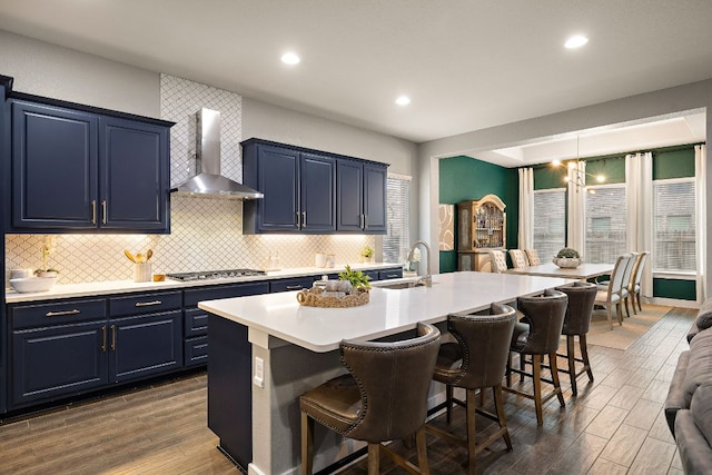 509 Leon Loop, Liberty Hill, TX 78642 - kitchen featuring wall chimney range hood, blue cabinetry, a sink, a kitchen bar, and recessed lighting