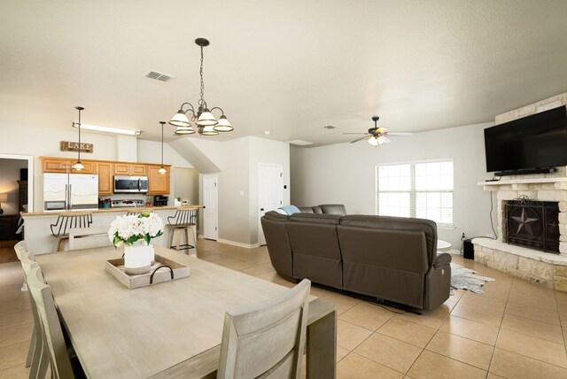 1526 Bonnyview Dr, Canyon Lake, TX 78133 - dining area featuring light tile patterned floors, a fireplace, a ceiling fan, a chandelier, and baseboards