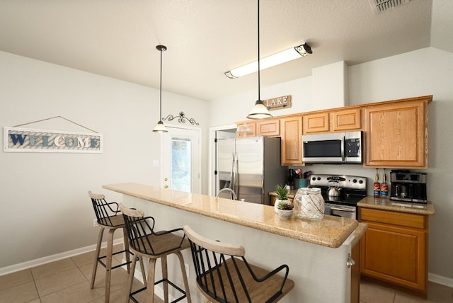 1526 Bonnyview Dr, Canyon Lake, TX 78133 - kitchen featuring appliances with stainless steel finishes, a kitchen bar, light tile patterned floors, and baseboards