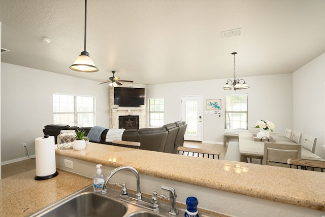 1526 Bonnyview Dr, Canyon Lake, TX 78133 - kitchen with a fireplace, ceiling fan, baseboards, pendant lighting, and tile patterned flooring
