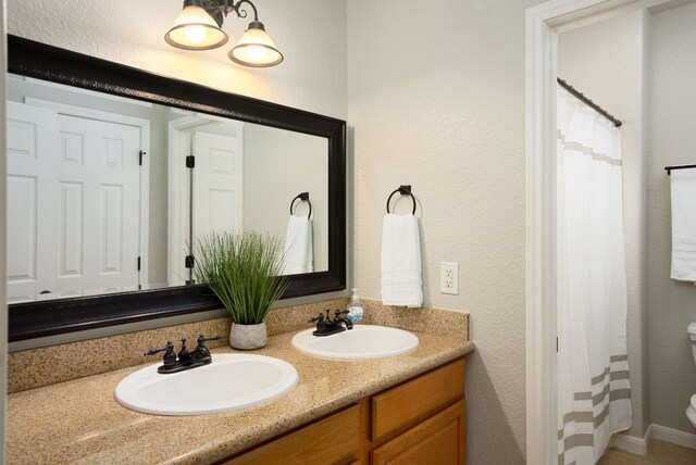 1526 Bonnyview Dr, Canyon Lake, TX 78133 - bathroom with toilet, double vanity, a shower with curtain, and a textured wall