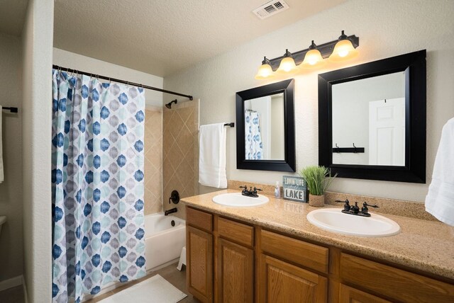 1526 Bonnyview Dr, Canyon Lake, TX 78133 - bathroom with double vanity, shower / tub combo, a textured ceiling, and toilet