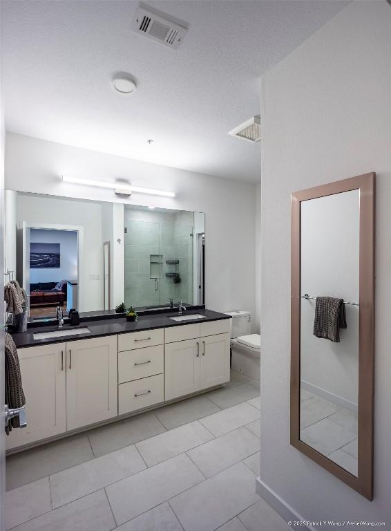 900 S 1st St Unit 416, Austin, TX 78704 - full bathroom featuring a stall shower, double vanity, toilet, tile patterned floors, and baseboards
