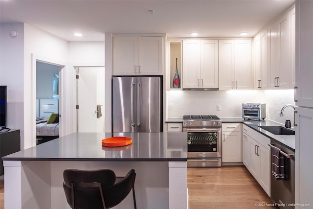 900 S 1st St Unit 416, Austin, TX 78704 - kitchen featuring appliances with stainless steel finishes, a sink, light wood-style flooring, white cabinetry, and recessed lighting