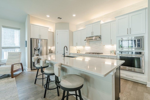 433 Skipping Cedar St, San Marcos, TX 78666 - kitchen featuring appliances with stainless steel finishes, a sink, under cabinet range hood, a kitchen bar, and backsplash