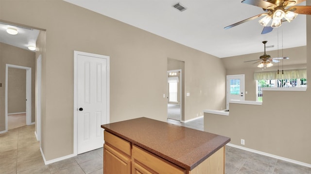 1803 Shooting Star Cv, Cedar Park, TX 78613 - kitchen with a ceiling fan, dark countertops, baseboards, light tile patterned floors, and a kitchen island