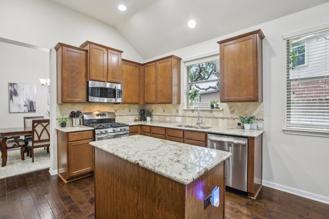 2228 Hilltop Climb Dr, Leander, TX 78641 - kitchen with appliances with stainless steel finishes, dark wood-type flooring, vaulted ceiling, decorative backsplash, and a center island