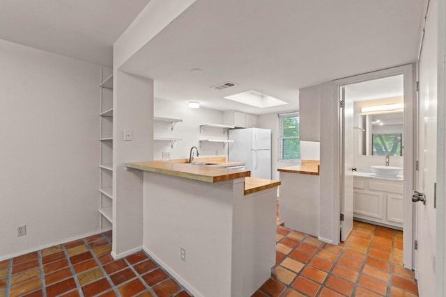 1135 Barton Hills Dr Unit 240, Austin, TX 78704 - kitchen featuring freestanding refrigerator, butcher block counters, open shelves, a peninsula, and a sink