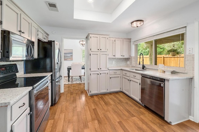 9417 Longvale Dr, Austin, TX 78729 - kitchen featuring appliances with stainless steel finishes, a sink, light wood-style flooring, and backsplash