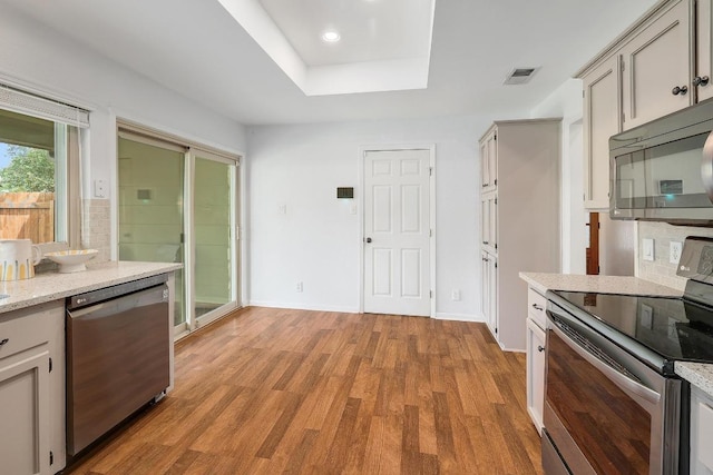 9417 Longvale Dr, Austin, TX 78729 - kitchen featuring stainless steel appliances, light wood-style floors, recessed lighting, a raised ceiling, and baseboards