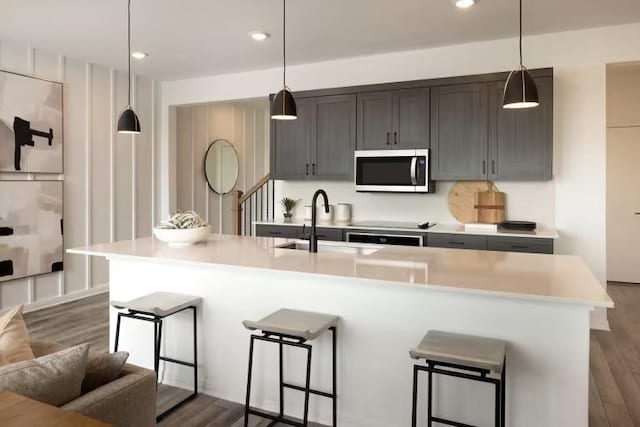 2725 Woodall Dr Unit 1602, Cedar Park, TX 78613 - kitchen with stainless steel microwave, a sink, light countertops, dark wood-type flooring, and a kitchen breakfast bar