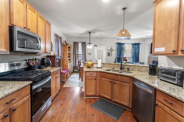 1115 Henderson Dr, Leander, TX 78641 - kitchen with stainless steel appliances, a peninsula, dark wood finished floors, pendant lighting, and light stone counters