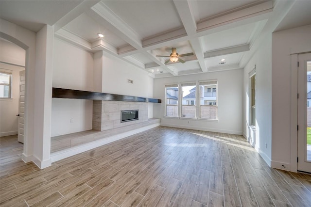 3321 Mongolian Dr, Leander, TX 78641 - unfurnished living room with beamed ceiling, light wood-style flooring, a tile fireplace, baseboards, and coffered ceiling