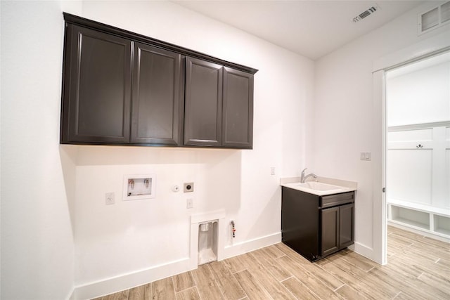 3321 Mongolian Dr, Leander, TX 78641 - laundry area with electric dryer hookup, gas dryer hookup, cabinet space, light wood finished floors, and hookup for a washing machine