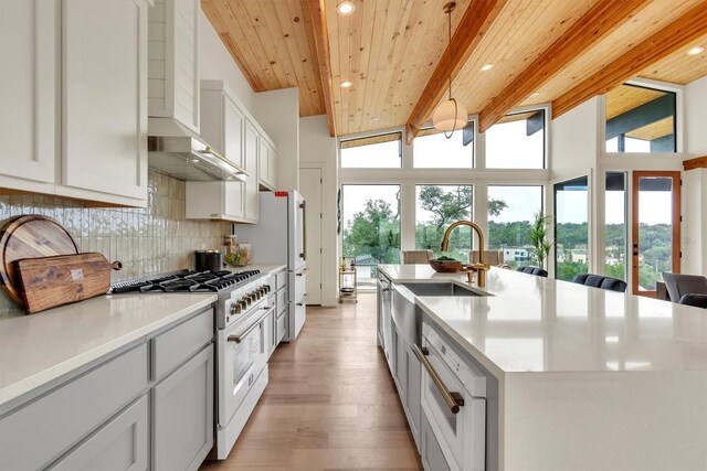 18408 F M Road 1431, Jonestown, TX 78645 - kitchen featuring high end stainless steel range, wall chimney range hood, recessed lighting, backsplash, and light wood-type flooring