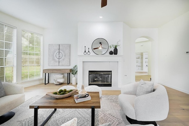 6116 Pebble Garden Ct, Austin, TX 78739 - living area featuring arched walkways, wood finished floors, a fireplace, a ceiling fan, and baseboards