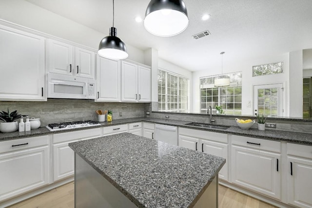 6116 Pebble Garden Ct, Austin, TX 78739 - kitchen featuring white appliances, a sink, backsplash, white cabinetry, and light wood-style floors
