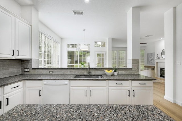 6116 Pebble Garden Ct, Austin, TX 78739 - kitchen featuring dishwasher, a sink, dark stone countertops, light wood finished floors, and plenty of natural light