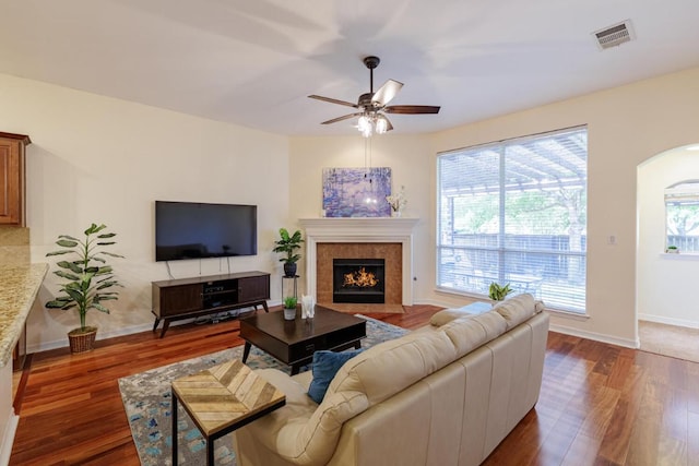 4308 Clear Meadow Pl, Round Rock, TX 78665 - living room featuring dark wood-style floors, a ceiling fan, a fireplace with flush hearth, and arched walkways