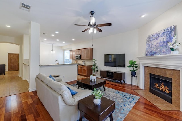 4308 Clear Meadow Pl, Round Rock, TX 78665 - living area featuring arched walkways, ceiling fan, light wood-type flooring, a tiled fireplace, and recessed lighting
