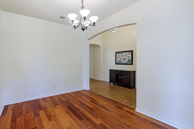4308 Clear Meadow Pl, Round Rock, TX 78665 - unfurnished dining area featuring arched walkways, a chandelier, wood finished floors, and baseboards