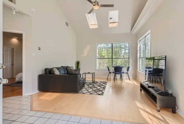 1202 Loma Dr, Austin, TX 78741 - living room featuring high vaulted ceiling, a skylight, a ceiling fan, wood finished floors, and track lighting