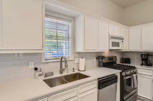 1202 Loma Dr, Austin, TX 78741 - kitchen featuring stainless steel appliances, a sink, white cabinets, and light countertops
