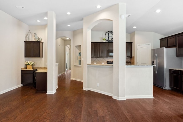 1610 Discovery Blvd, Cedar Park, TX 78613 - kitchen featuring stainless steel fridge with ice dispenser, dark brown cabinetry, decorative backsplash, arched walkways, and dark wood-style floors