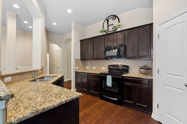 1610 Discovery Blvd, Cedar Park, TX 78613 - kitchen with black appliances, arched walkways, light stone countertops, dark wood finished floors, and tasteful backsplash