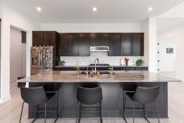 216 Reata Ridge Loop, Liberty Hill, TX 78642 - kitchen featuring stainless steel fridge with ice dispenser, under cabinet range hood, tasteful backsplash, light stone counters, and recessed lighting