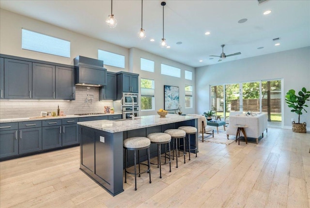 3004 Hunt Trl, Austin, TX 78757 - kitchen with wall chimney exhaust hood, ceiling fan, light wood-type flooring, light stone countertops, and recessed lighting
