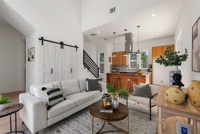 106 W Croslin St Unit B, Austin, TX 78752 - living room featuring light wood-style floors, a barn door, a high ceiling, stairway, and recessed lighting