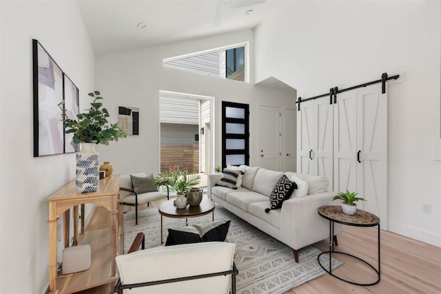 106 W Croslin St Unit B, Austin, TX 78752 - living room with a barn door, light wood-style flooring, a towering ceiling, and baseboards