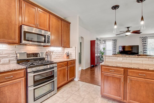 14028 Turkey Hollow Trl, Austin, TX 78717 - kitchen with stainless steel appliances, arched walkways, a ceiling fan, decorative backsplash, and brown cabinetry