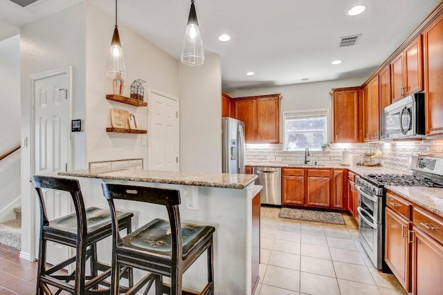 14028 Turkey Hollow Trl, Austin, TX 78717 - kitchen with stainless steel appliances, a sink, a breakfast bar area, decorative backsplash, and light stone counters