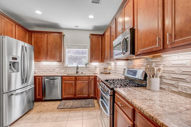 14028 Turkey Hollow Trl, Austin, TX 78717 - kitchen featuring stainless steel appliances, a sink, brown cabinets, light stone countertops, and backsplash