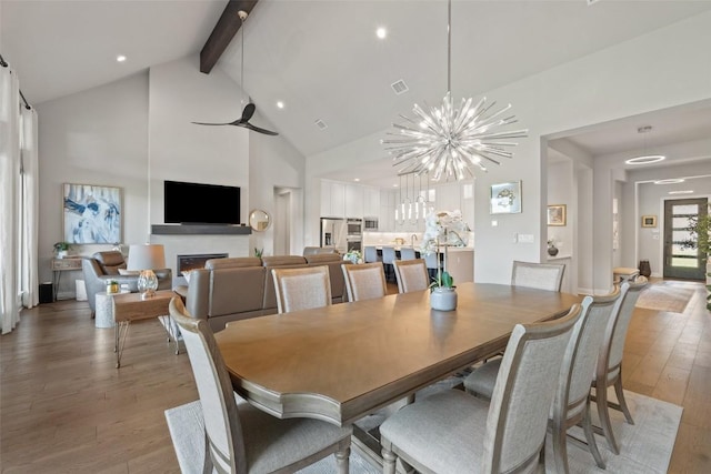 158 Baldovino Skwy, Lakeway, TX 78738 - dining room with beam ceiling, high vaulted ceiling, light wood finished floors, a glass covered fireplace, and a chandelier