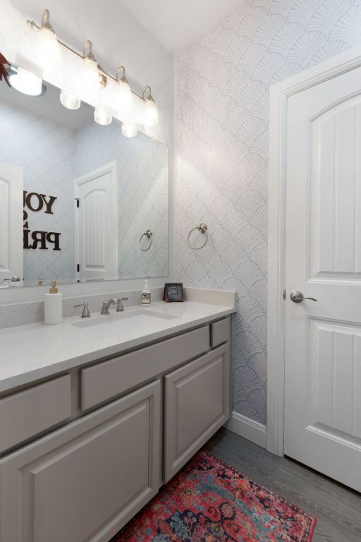 110 Lakecliff Cv, Kingsland, TX 78639 - bathroom featuring wallpapered walls, wood finished floors, vanity, and baseboards