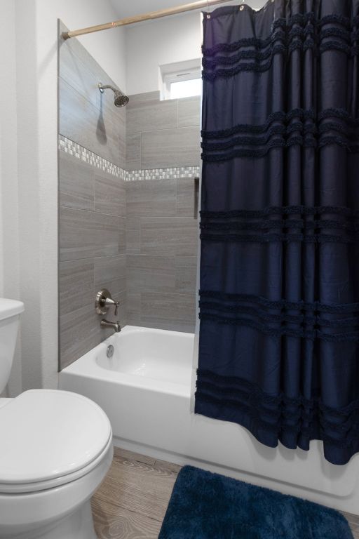 110 Lakecliff Cv, Kingsland, TX 78639 - bathroom featuring shower / bathtub combination with curtain and toilet