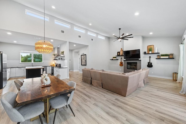 20702 Post Oak Dr, Lago Vista, TX 78645 - dining area with a chandelier, recessed lighting, light wood-style flooring, a glass covered fireplace, and baseboards