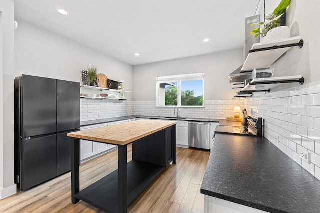 20702 Post Oak Dr, Lago Vista, TX 78645 - kitchen with open shelves, stainless steel appliances, butcher block countertops, decorative backsplash, and white cabinetry