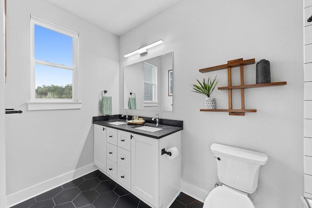 20702 Post Oak Dr, Lago Vista, TX 78645 - bathroom featuring toilet, baseboards, double vanity, and tile patterned flooring