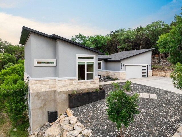 20702 Post Oak Dr, Lago Vista, TX 78645 - contemporary house featuring stone siding, concrete driveway, a garage, and stucco siding